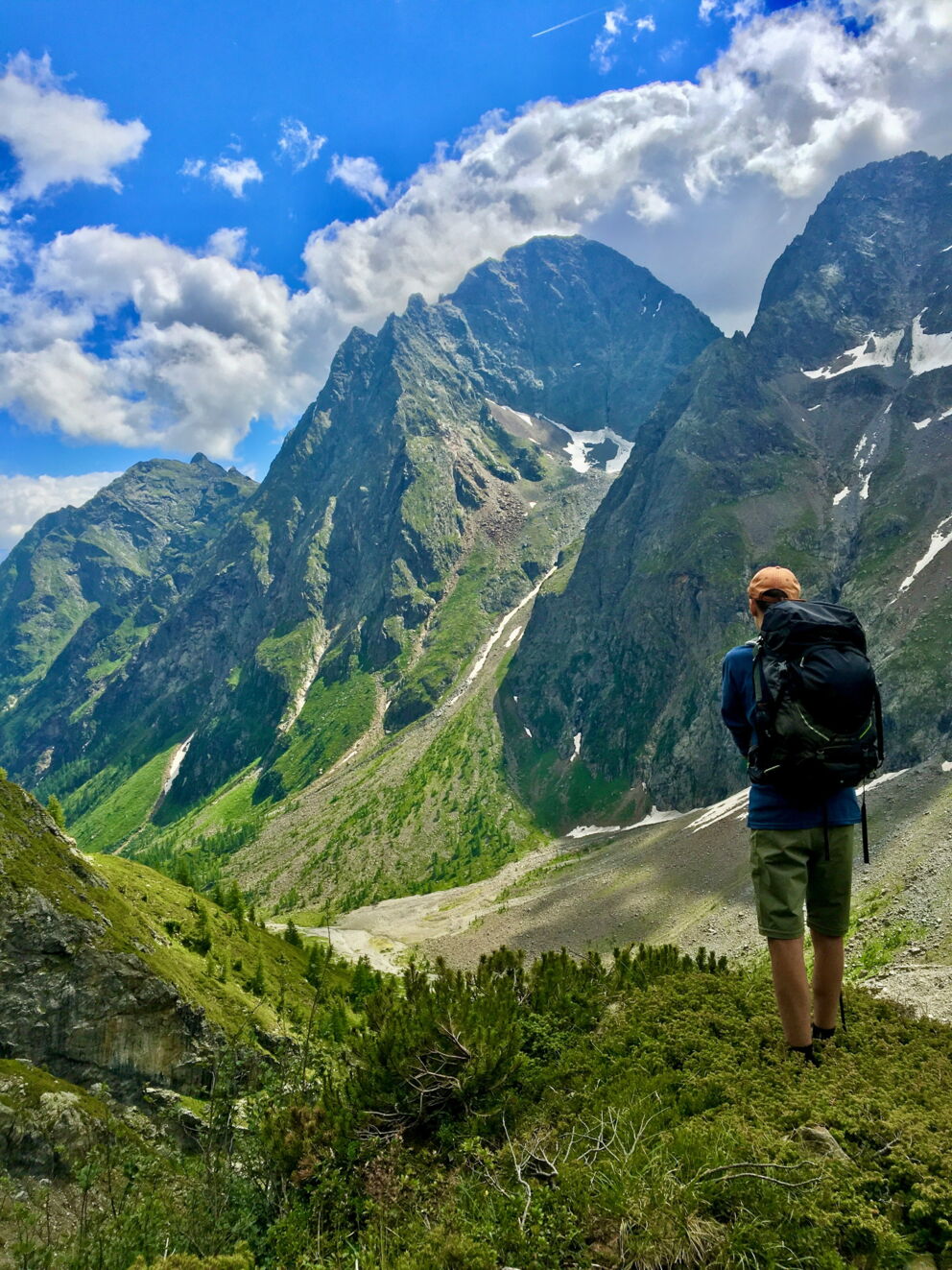 Hikers look out over impressive peaks under a bright blue sky in the Alps.