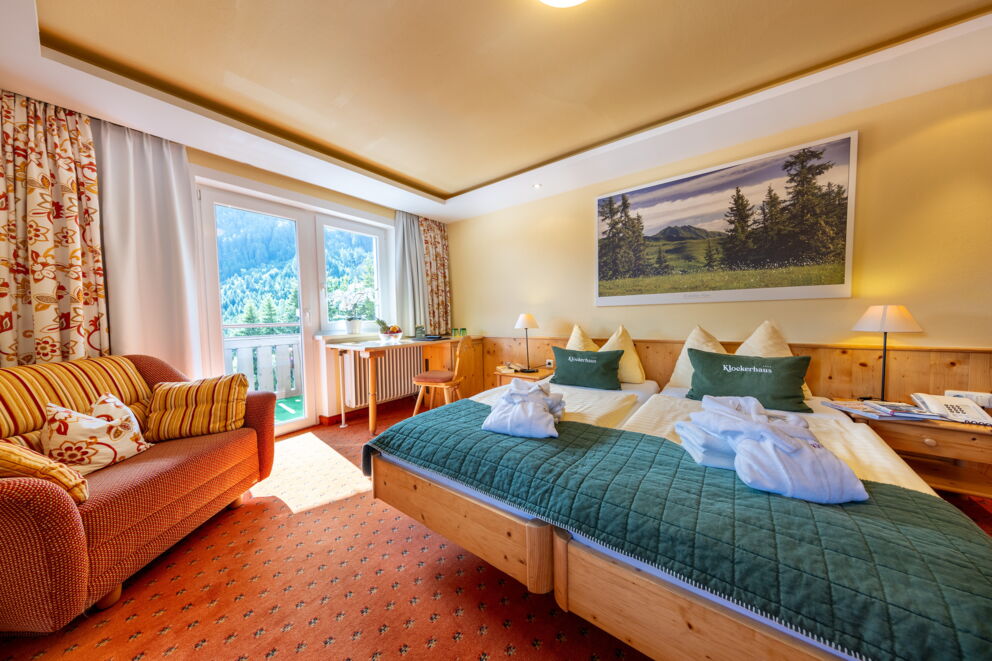 Helles Zimmer mit Alpenblick, gemütlicher Sitzgelegenheit und einladendem Doppelbett.