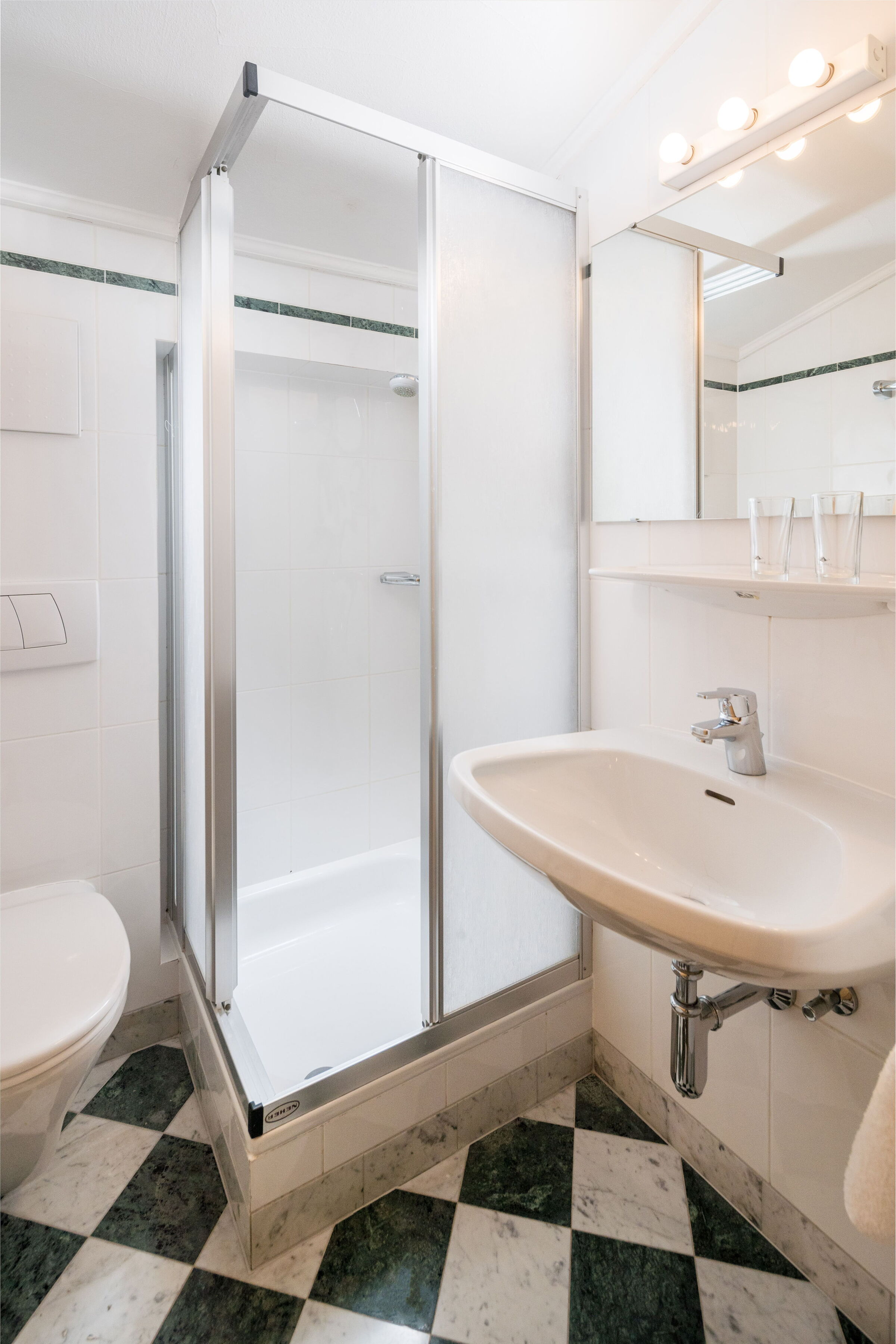 Helles Badezimmer mit Dusche, Waschbecken und WC, in eleganter Ausstattung.