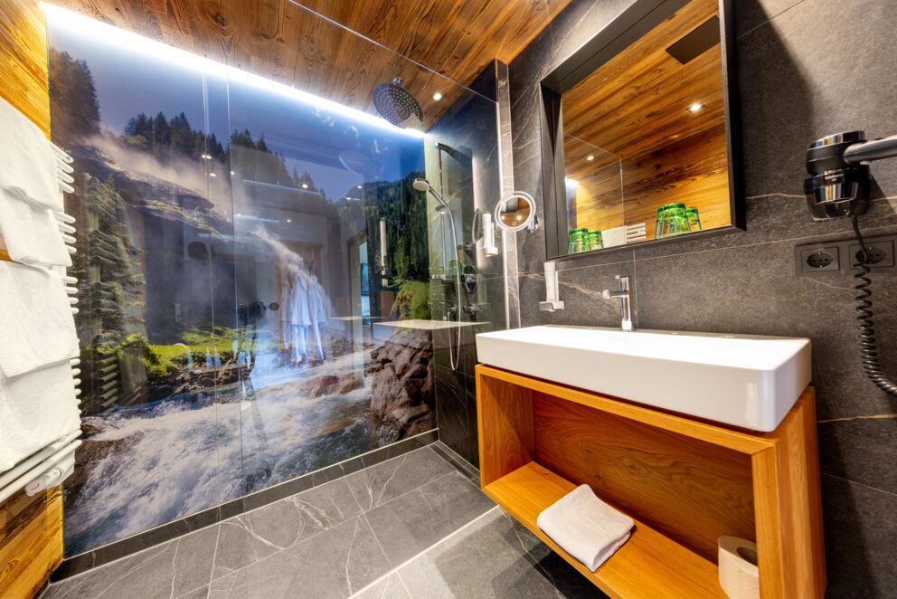 Modernes Badezimmer mit Holzdetails und Glaswand, die Wasserfälle zeigt.