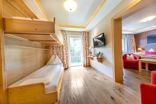 Helles Familienzimmer mit Stockbetten, Holzböden und Balkon im Hotel Klockerhaus.
