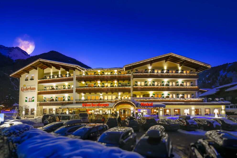 Hotel Klockerhaus with festive lighting and snow-covered mountains in the background.