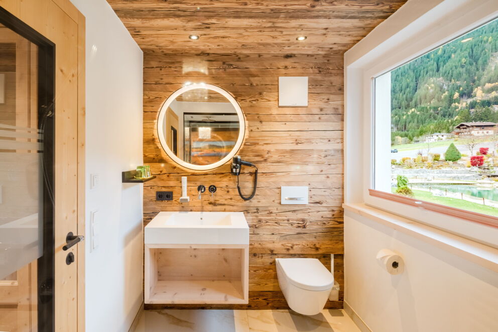 Modernes Badezimmer des Kuschelzimmers mit Holzoptik, runder Spiegel und Dusche