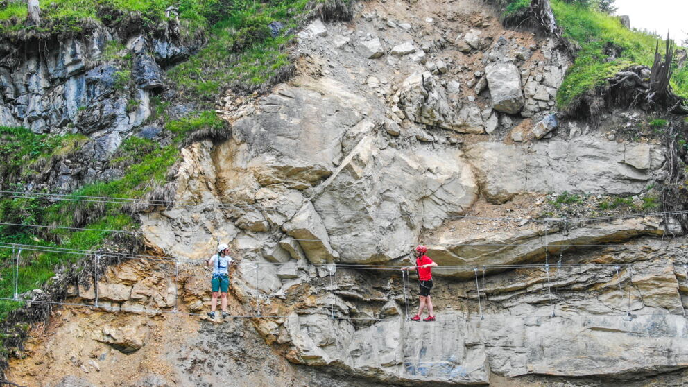 Two people on the Riederklamm via ferrata near Gerlos, standing in front of a steep rock face. © TVB Zillertal Arena