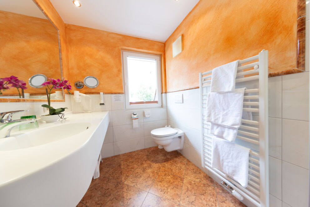 Modernes Badezimmer mit warmen Farben, frischen Handtüchern und stilvollen Akzenten.