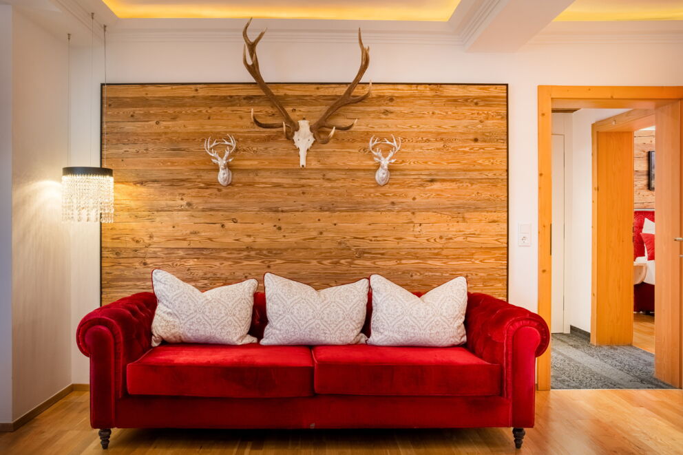 Wohnbereich der Kuschelsuite "Superior" mit rotem Sofa und Holzwand