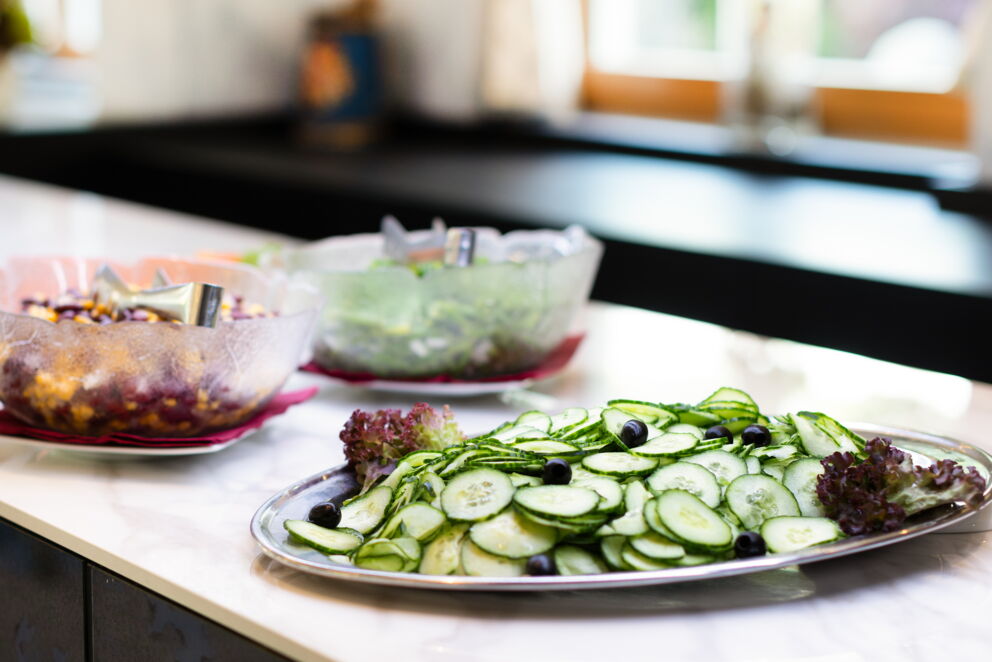 Frischer Gurkensalat mit Oliven, umgeben von köstlichen Beilagen auf einem Tisch.