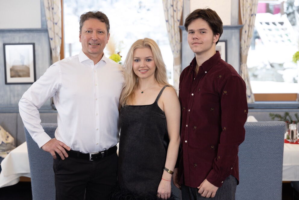 Drei Personen lächeln im eleganten Hotelinterieur der Gastfreundschaft entgegen.