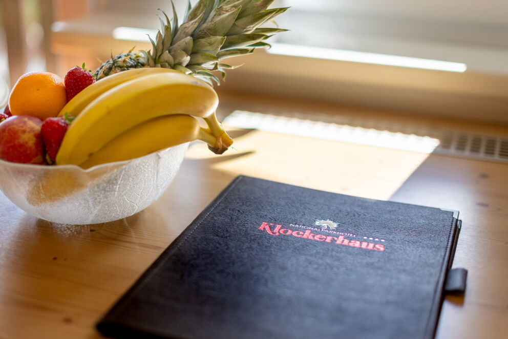 Obstschale mit Ananas, Bananen, Orangen und Erdbeeren auf einem Holztisch.