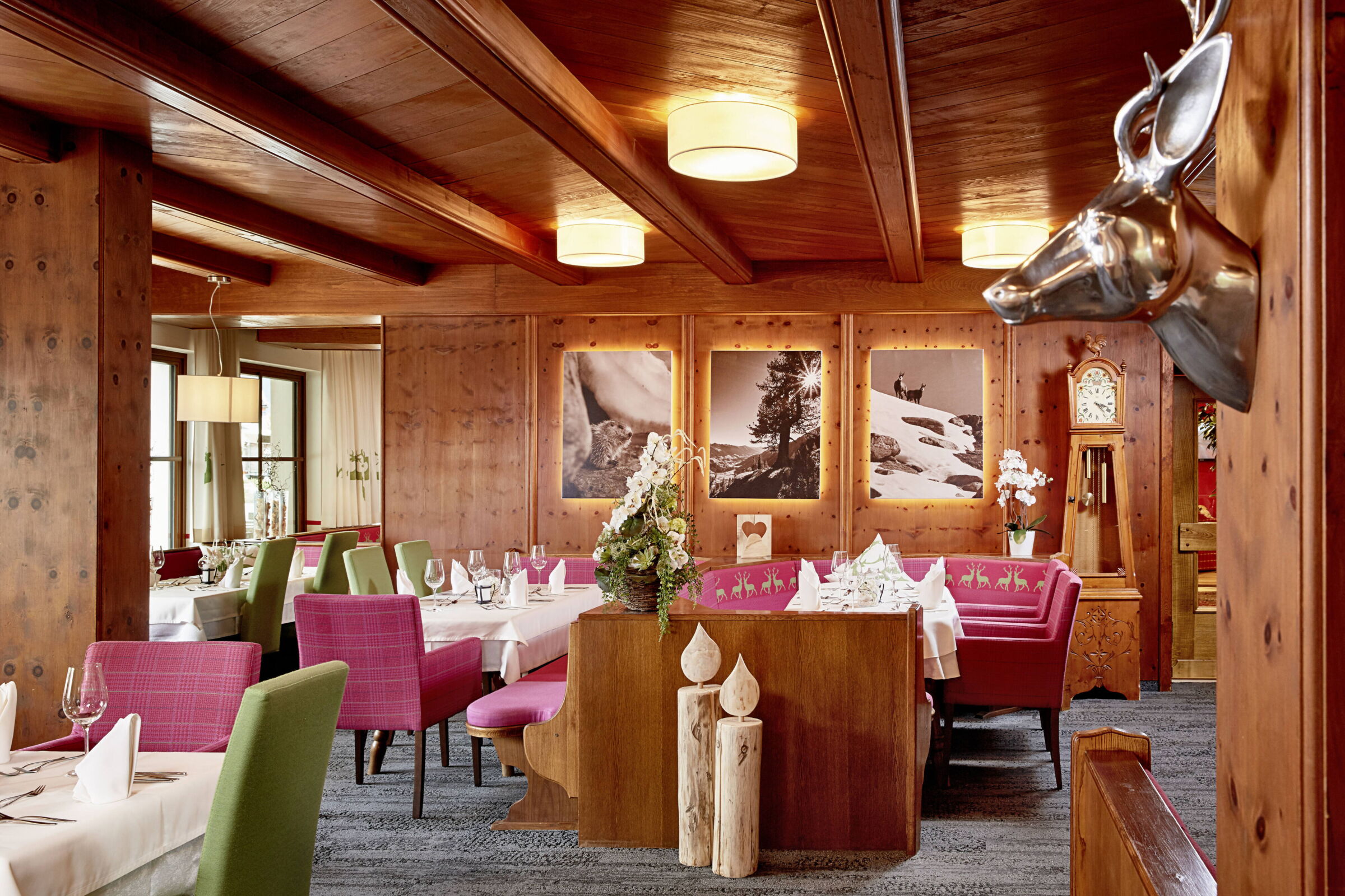 Elegantes Restaurant mit Holzverkleidung, farbenfrohen Stühlen und dekorativen Bildern an der Wand.