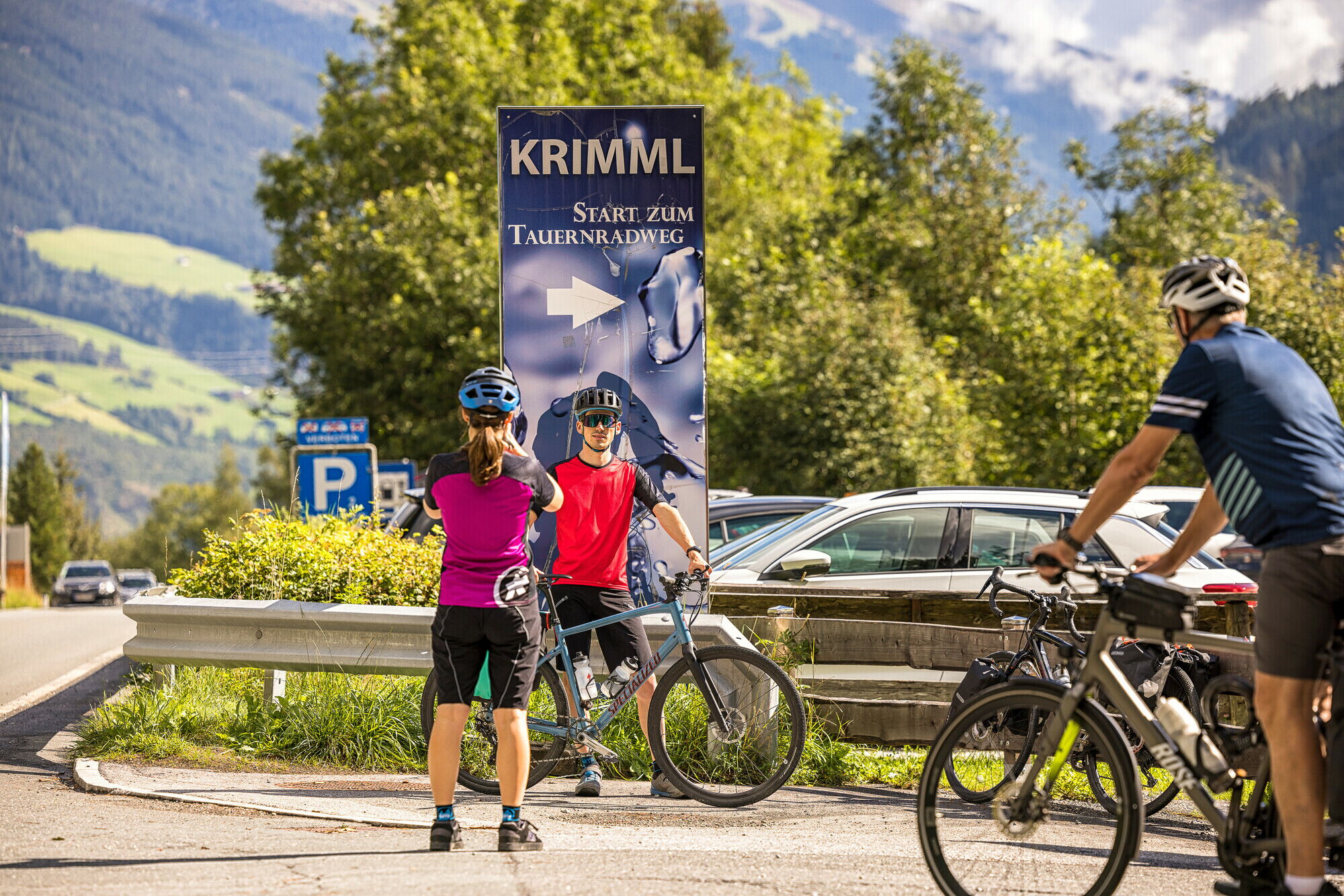 Cyclists at the starting point of the Tauern Cycle Path in Krimml in sunny weather.