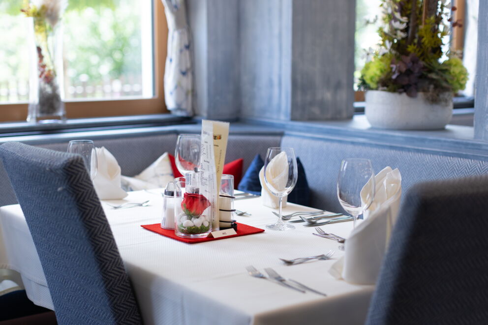 Stilvoll gedeckter Esstisch mit Gläsern, Besteck und Blumendekoration in elegantem Ambiente.