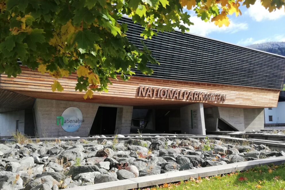 Modernes Gebäude des Nationalparkzentrums mit hölzerner Fassade und grünem Baum.