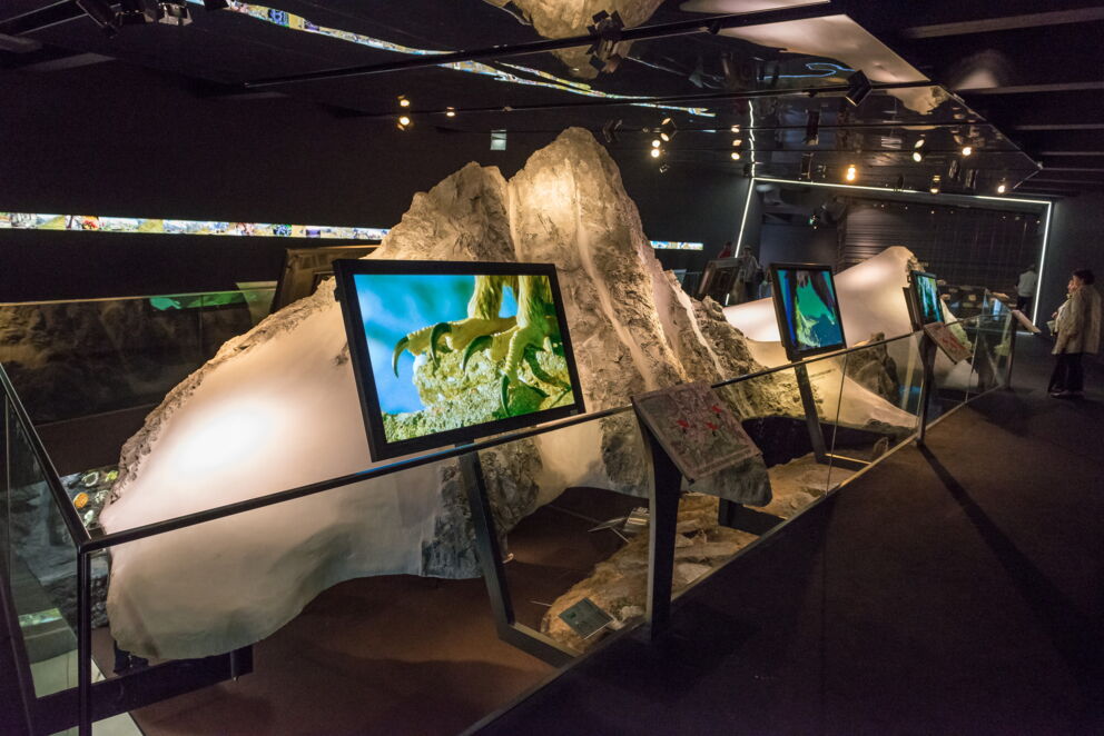 Modern exhibition with screens and rocks in a dark room