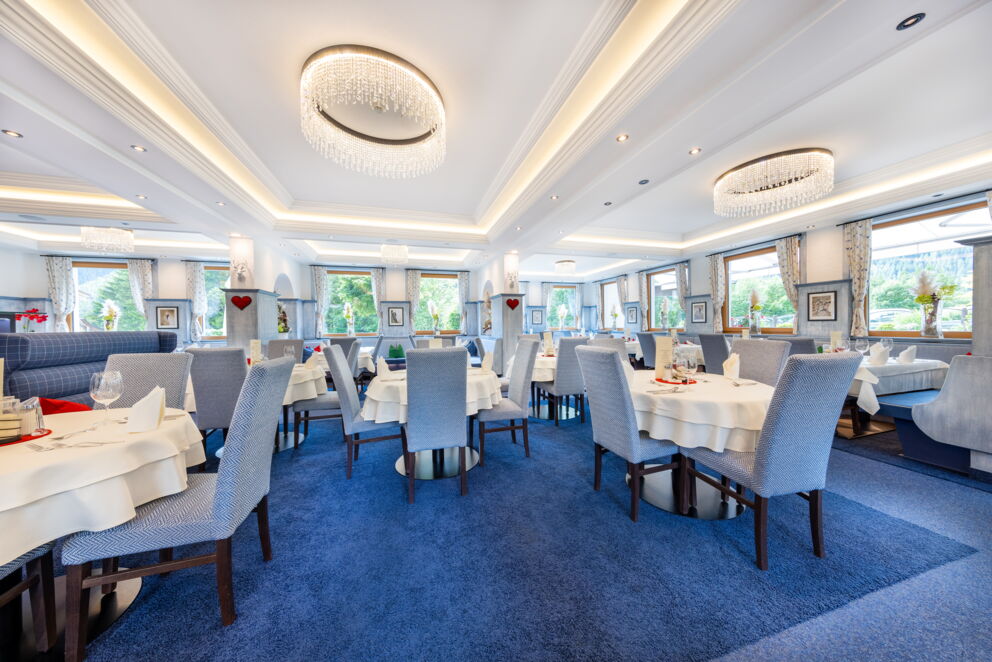 Helles Restaurant mit stilvollen Kronleuchtern und gedeckten Tischen im Hotel Klockerhaus.
