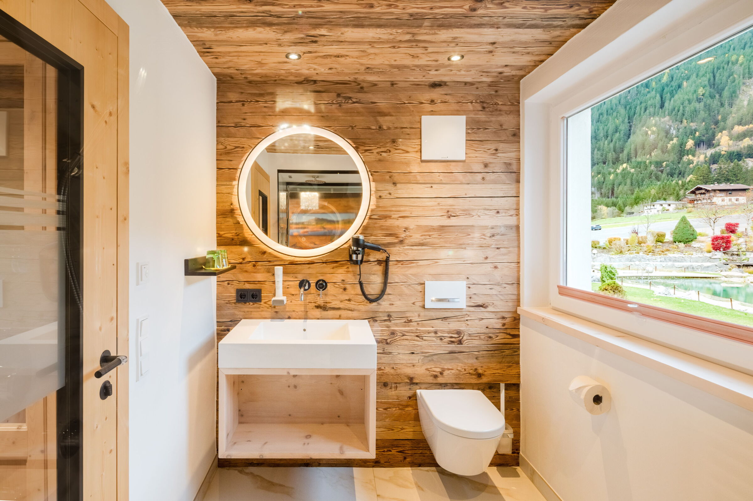Modern bathroom of the Cozy Room with wood-look, round mirror, and shower