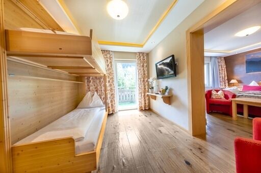 Helles Familienzimmer mit Stockbetten, Holzböden und Balkon im Hotel Klockerhaus.
