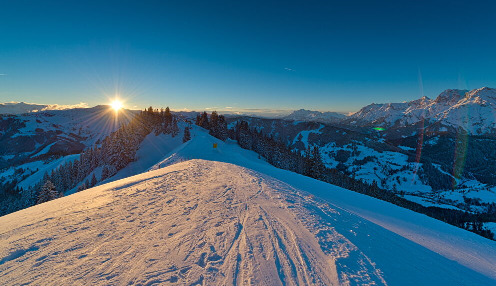 Schneeberge bei Sonnenuntergang mit Blick auf verschneite Täler und Wälder.