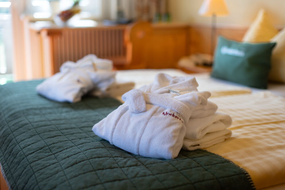 Weiche, weiße Bademäntel auf einem gemütlichen Bett im Hotelzimmer.