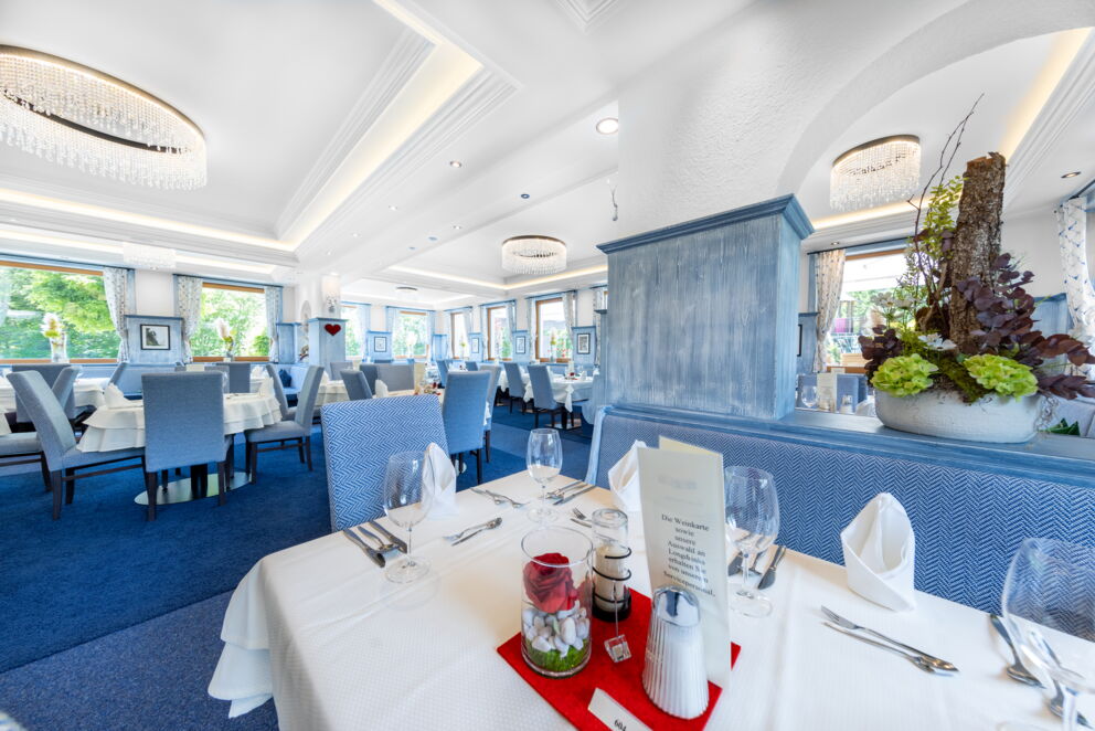 Helles Restaurant mit stilvoll gedeckten Tischen und eleganten Kronleuchtern.