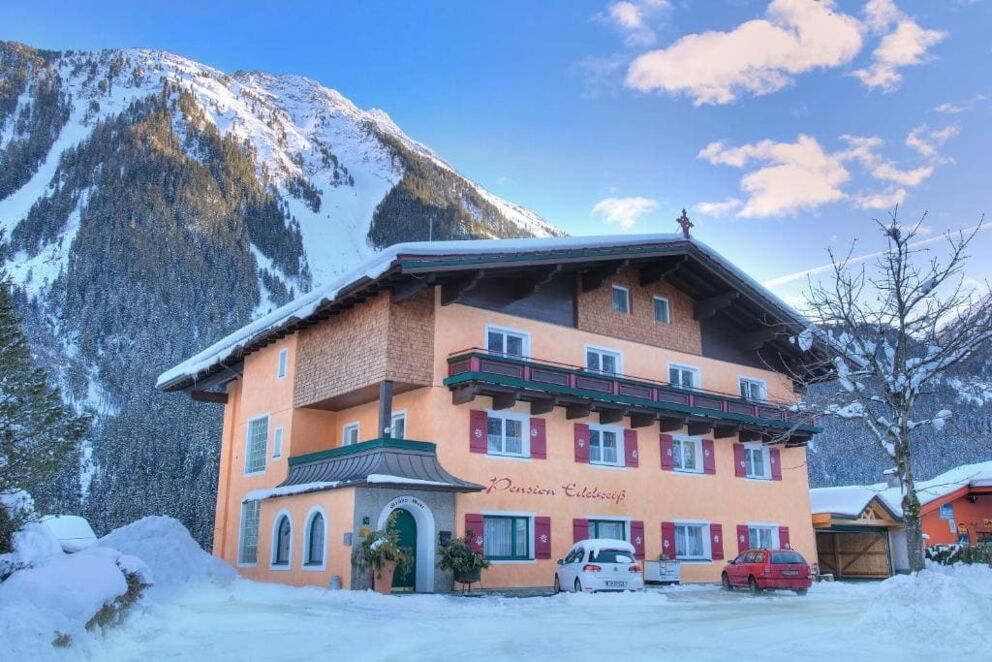 A traditional hotel in front of snow-covered mountains and clear skies in winter.