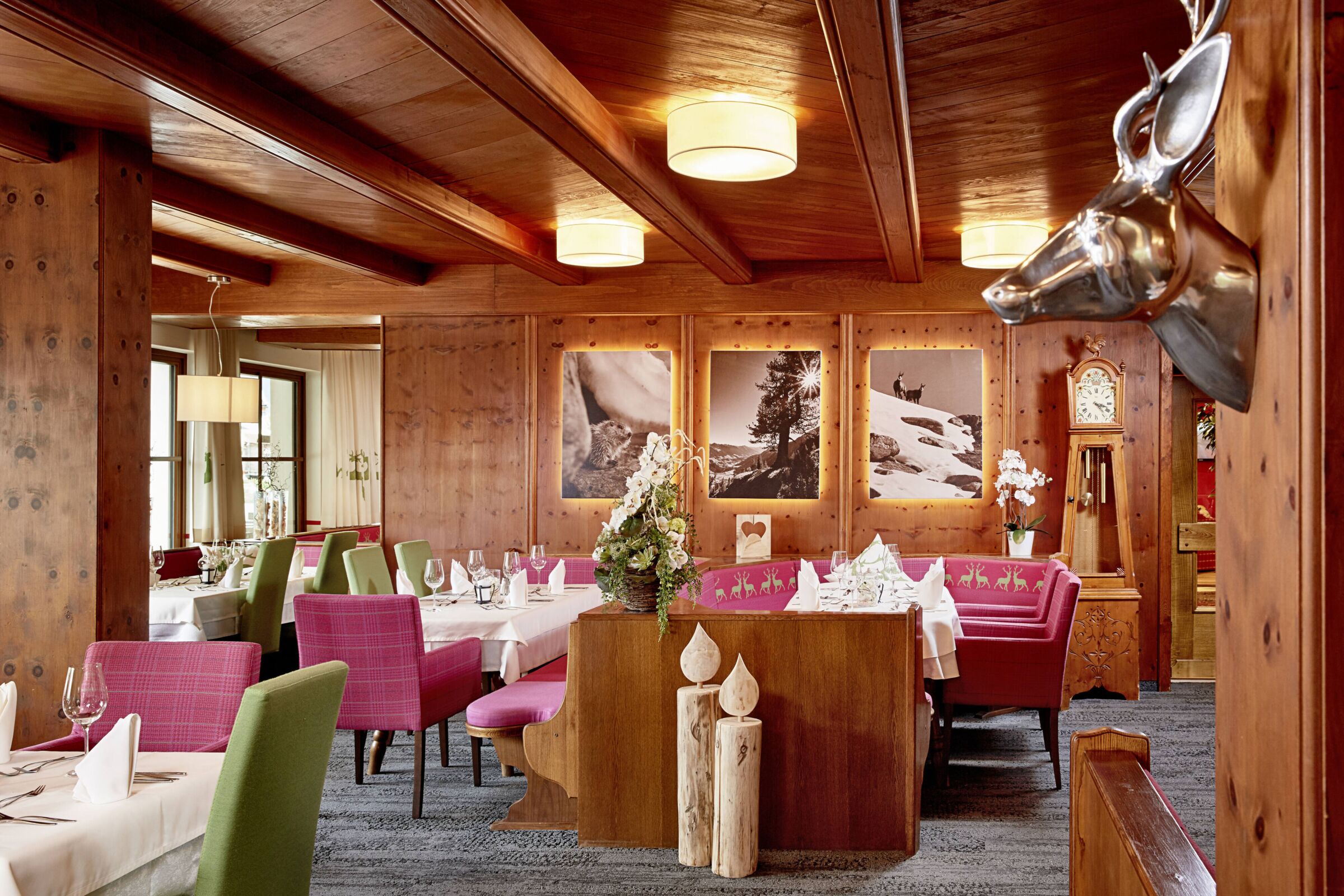 Elegantes Restaurant mit Holzverkleidung, farbenfrohen Stühlen und dekorativen Bildern an der Wand.
